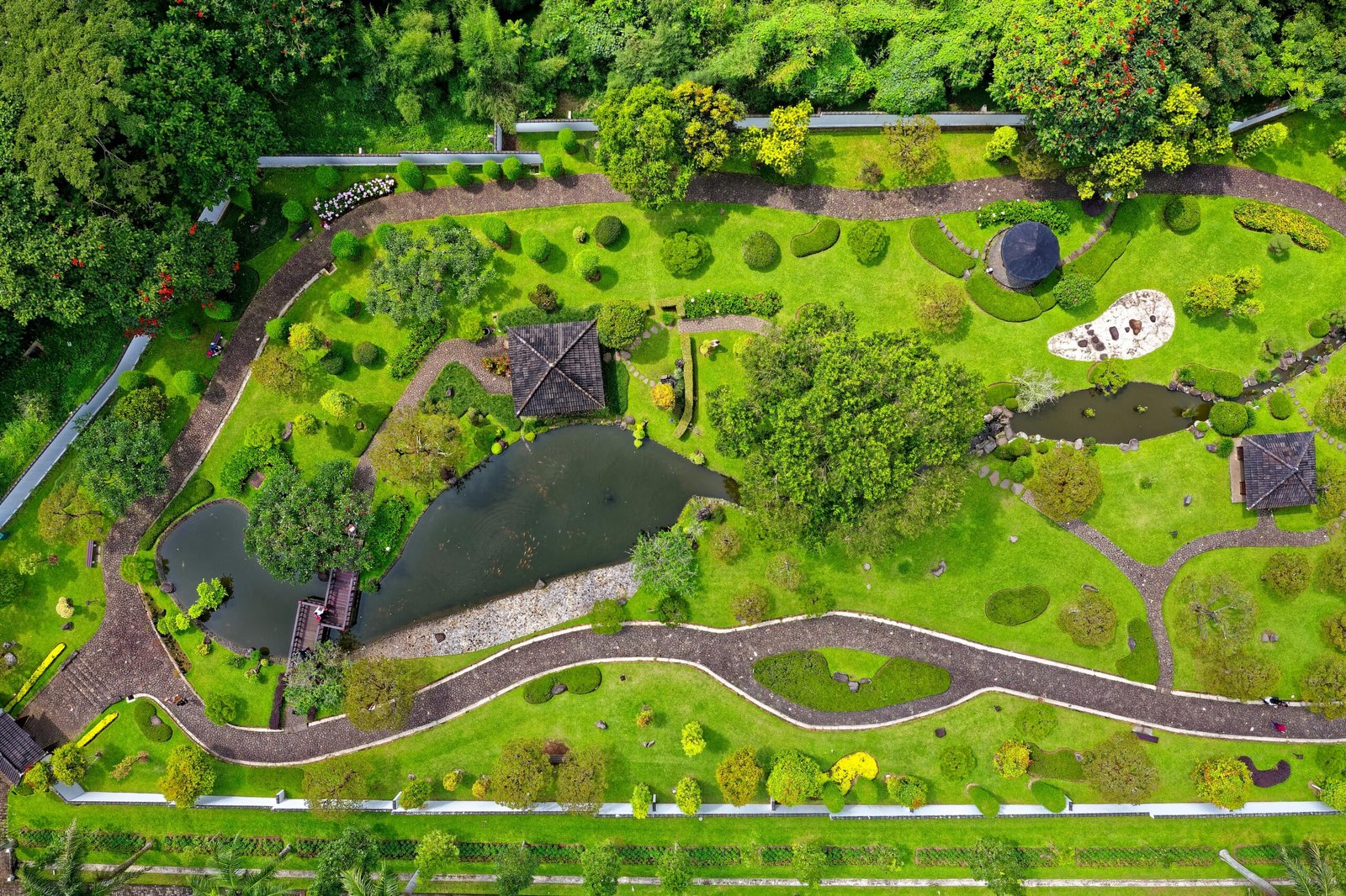 Stunning aerial shot capturing a lush garden with pathways, ponds, and vibrant greens.