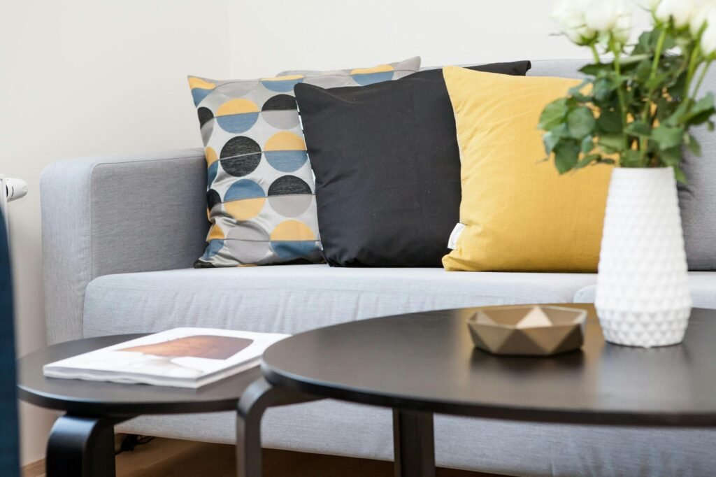 Contemporary living room interior featuring a stylish sofa, decorative pillows, and a vase of flowers.