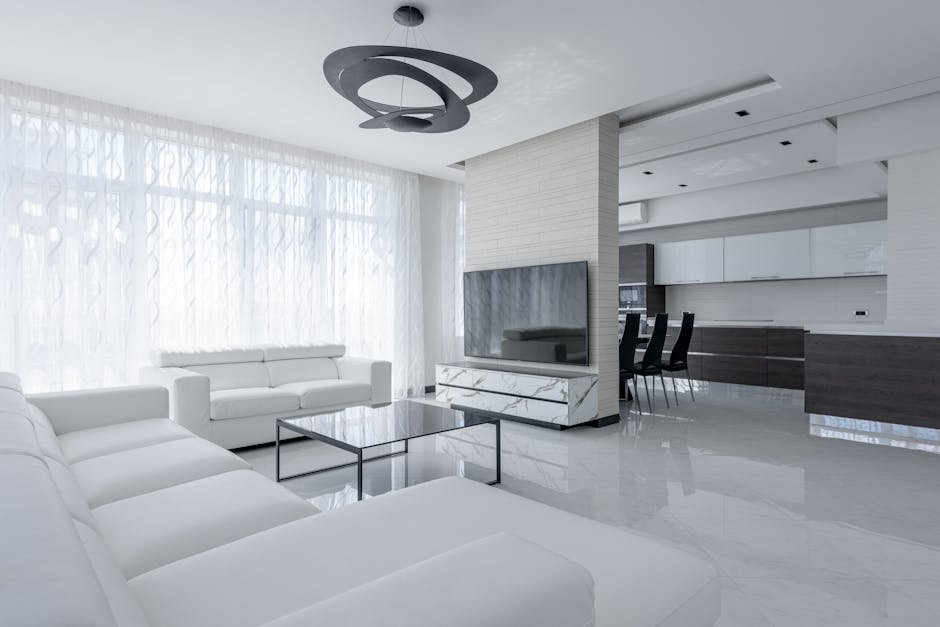 Interior of light apartment with table and couch near TV with cabinet and white walls near window with curtains and stool near lamp