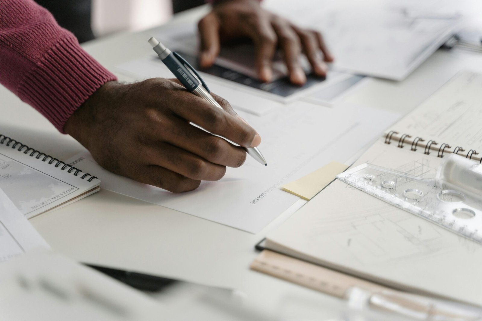 Close-up of architect drafting on blueprints in a modern office environment.