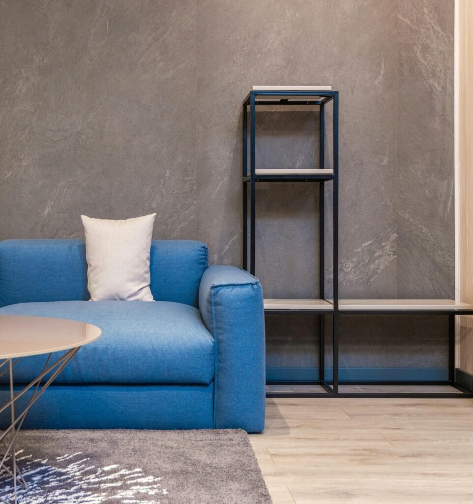 Stylish minimalist living room featuring a blue sofa and modern shelving unit.