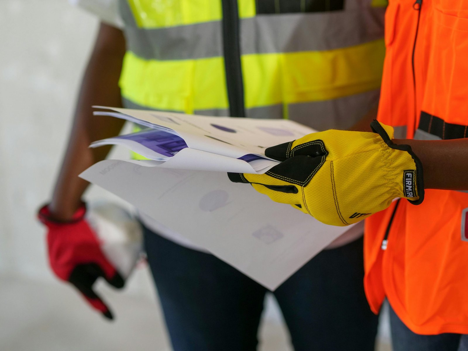 Close-up of construction workers reviewing documents wearing protective gear. Safety-focused interaction.